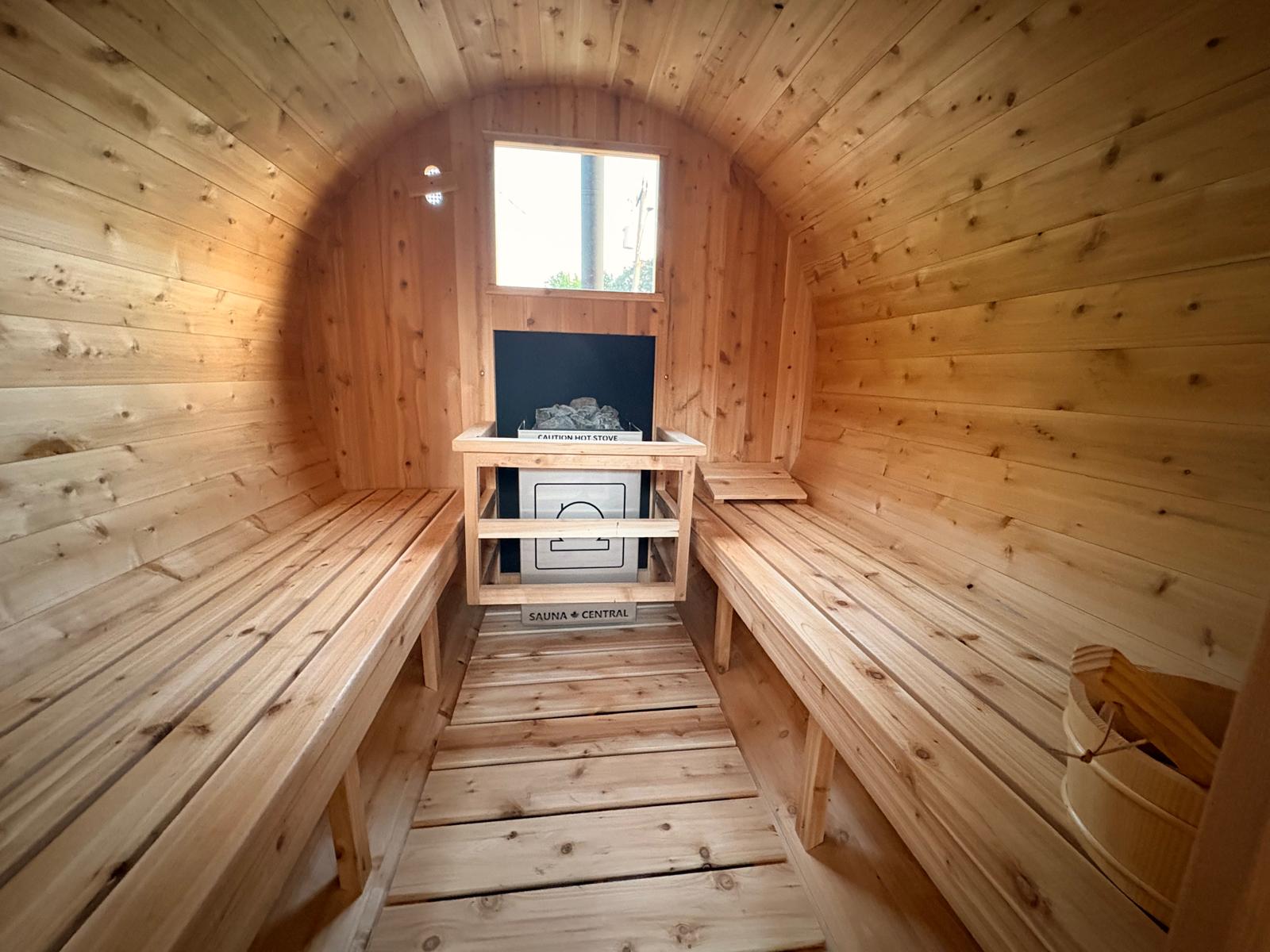 Nord Steam sauna interior — cedar barrel ceiling, benches, and wood stove with heated stones